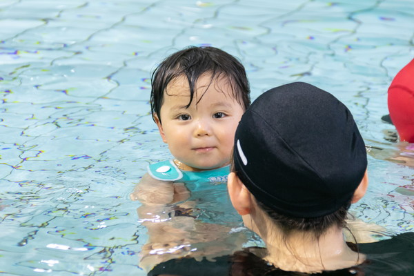 ライフジャケットを着てプールに浮かぶ赤ちゃん